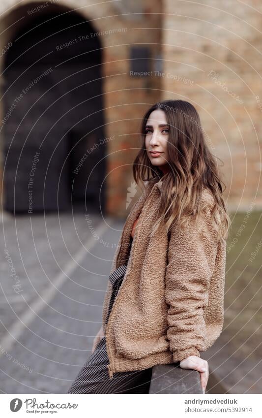 Fashion style portrait. beautiful stylish girl with long hair walks in the city. Portrait of attractive girl on the street. Spring or fall day. selective focus.