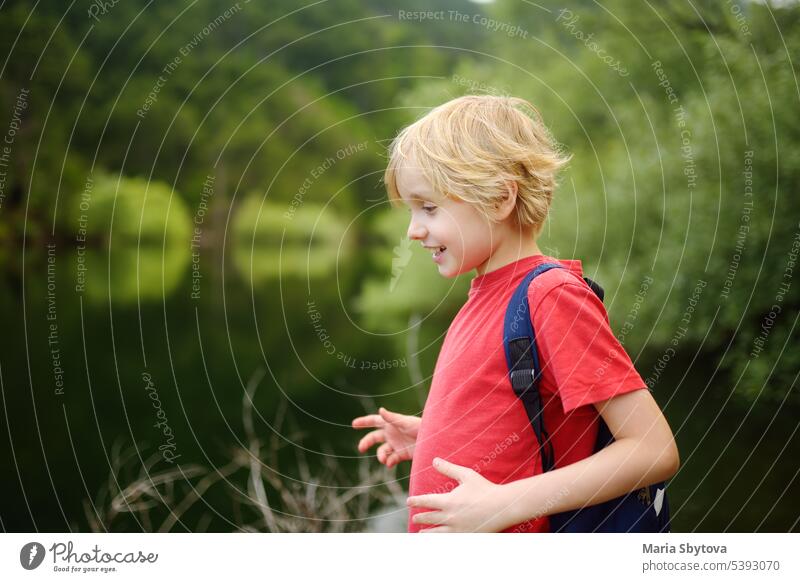 School child is hiking and exploring nature in forest. Preteen boy travel in woodland. Summer vacation activity for inquisitive kids in parkland. Adventure, scouting, tourism for kids