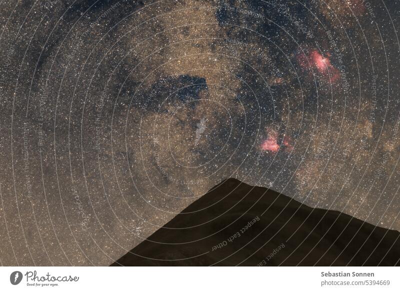 Stars at the night sky with M16 and M17 nebulae in the constellation of Sagittarius over a mountain peak of the Pyrenees, France star space astronomy abstract