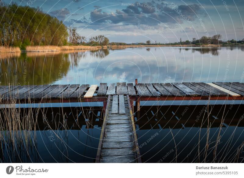 A jetty made of wooden planks on a calm lake pier water outdoor sky peaceful blue holiday nature beautiful bridge landscape summer horizon background boat scene