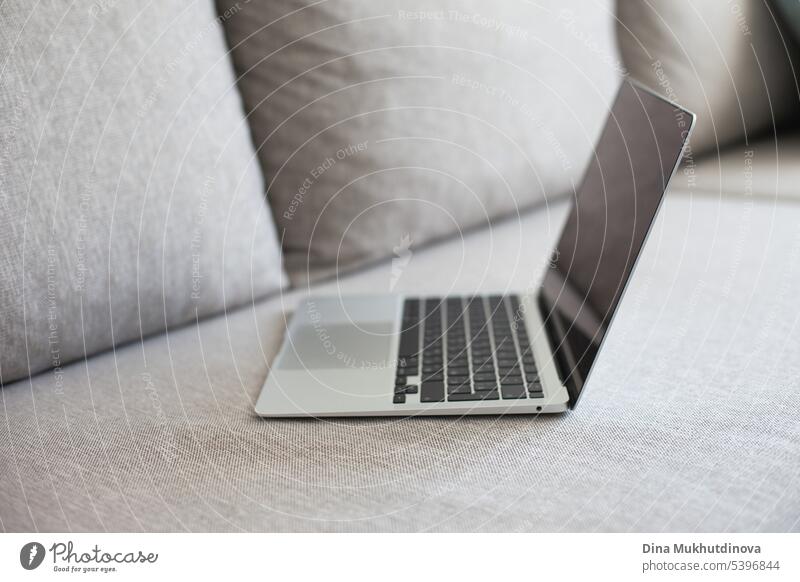 Silver and black laptop on grey couch. Remote job workspace, working from home. background blank business businessman casual comfortable communication computer