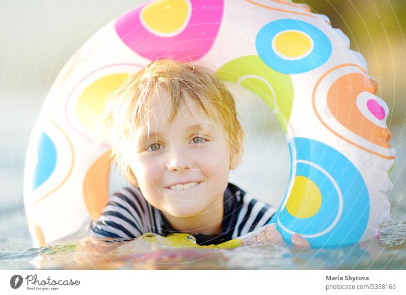 Little boy swimming with colorful floating ring in sea on sunny summer day. Cute child playing in clean water. Family and kids resort holiday during summer vacations.