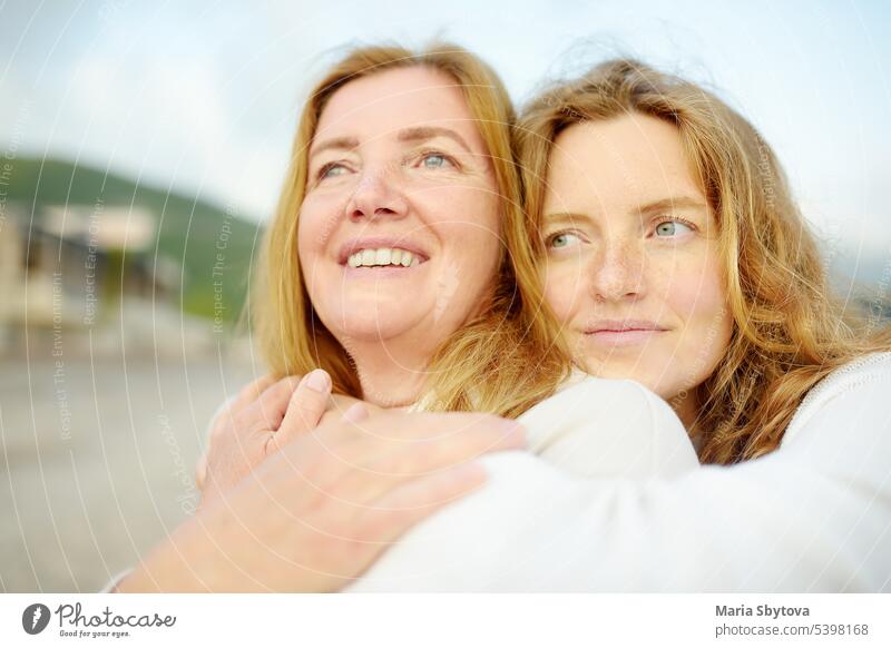 Redhead senior mother and her beautiful adult daughter are embracing. Family relationships between adult children and older parents. Close-up portrait of two generations of family.