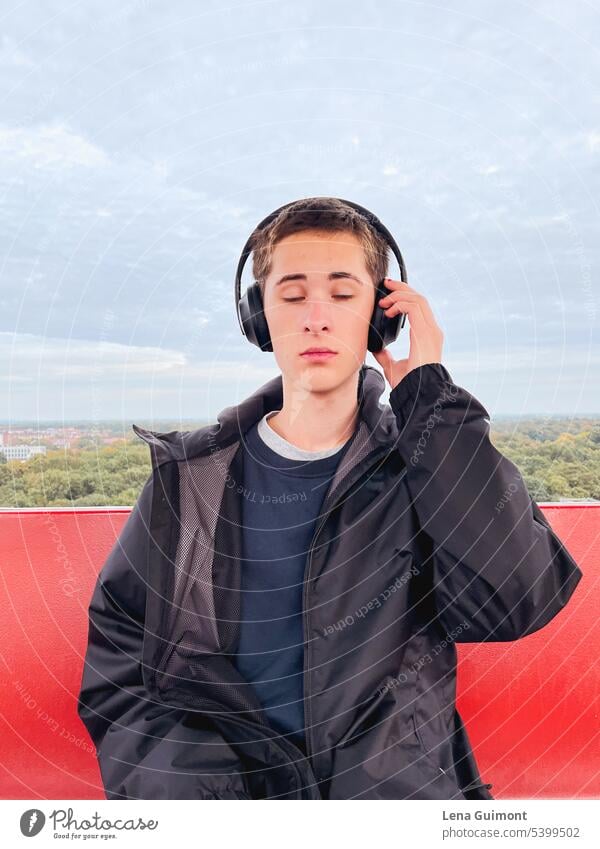 Teen in Ferris wheel with headphones teenager Headphones Music Listen to music Joy Technology youthful Lifestyle Boy (child) Smiling Brunette