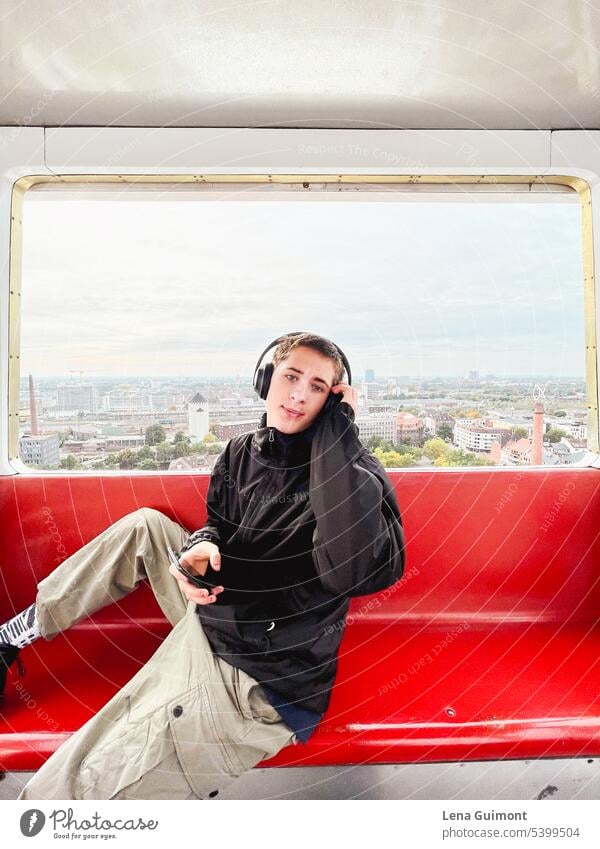 Teen in Ferris wheel with headphones teenager Headphones Music Listen to music Joy Technology youthful Lifestyle Boy (child) Smiling Brunette