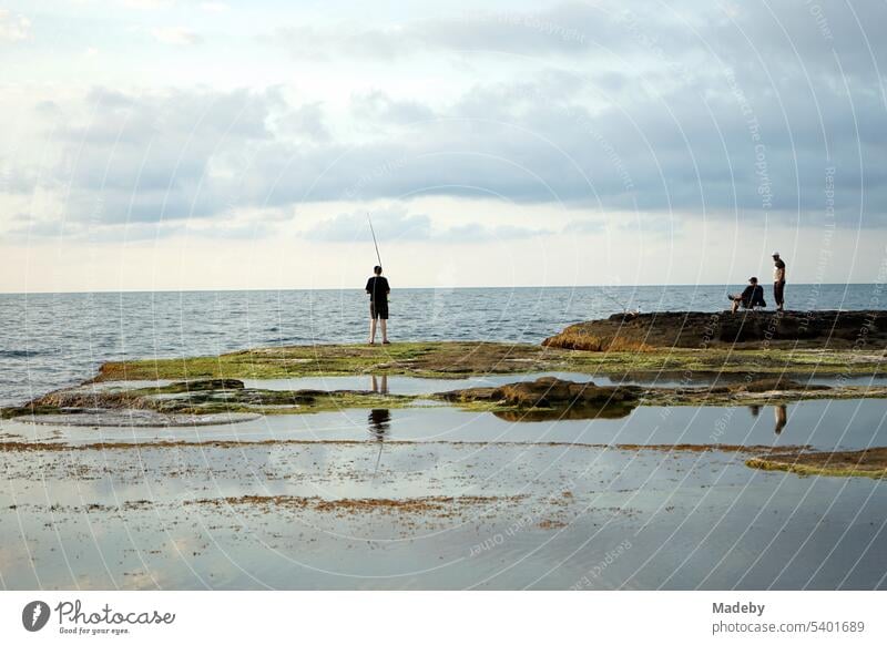 Anglers in summer with clouds and sunshine at the Pink Rock on the coast of the Black Sea in Kefken in the province of Kocaeli in Turkey Fishing (Angle) fishing