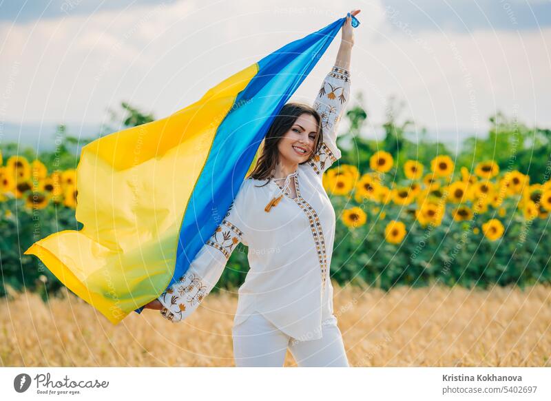 Young ukrainian woman waving national flag on sunflowers, wheat field background freedom girl independence outdoors patriot patriotic patriotism symbol ukraine