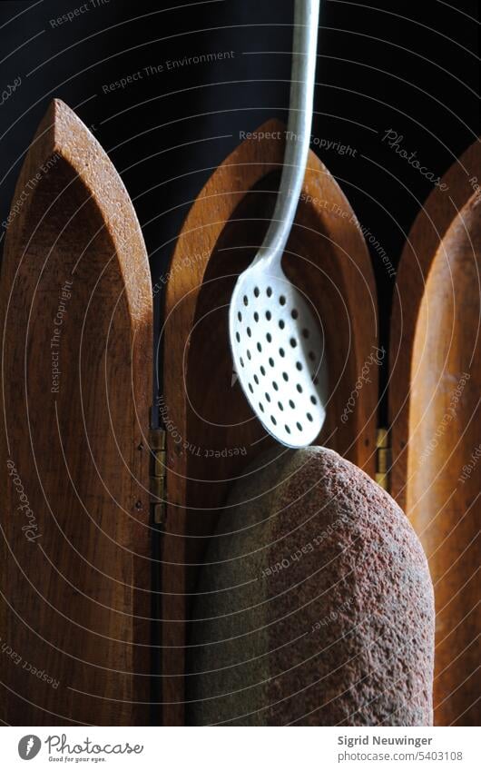 A wooden traveling wing altar houses a red and white sandstone that projects downward and a ladle that projects upward from the centerpiece. The ladle stands on top of the stone and crosses the top of the centerpiece. Metaphors for what?