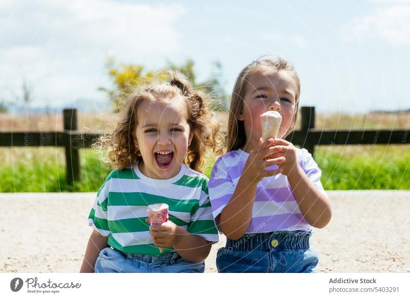 Happy little girls eating ice cream happy park picnic sister dessert kid tasty smile cheerful childhood joy enjoy positive sibling optimist laugh content fresh