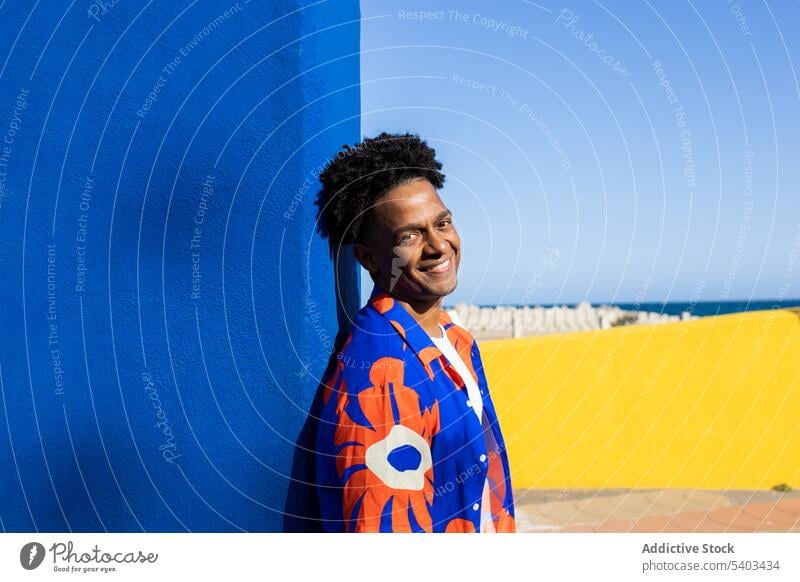 Happy young man in stylish clothes cheerful shirt happy positive wall urban glad outfit style smile black african american male content ethnic colorful fashion