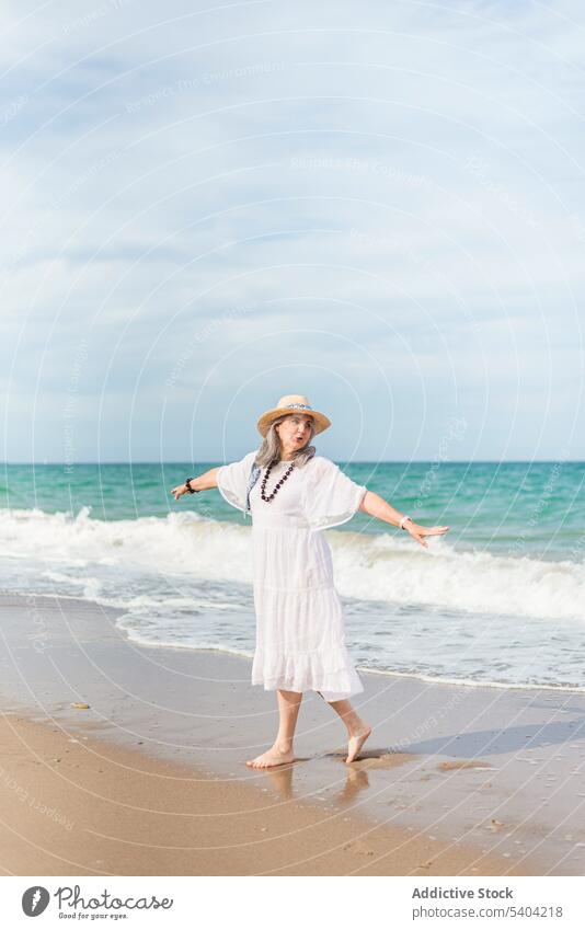 Positive woman walking on sandy beach happy freedom enjoy vacation summer sea nature elderly senior pensioner aged mature shore wave old water seashore coast