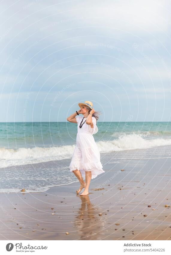 Happy woman walking on sandy beach freedom enjoy vacation summer sea nature elderly senior pensioner aged shore sky wave water seashore coast female ocean old