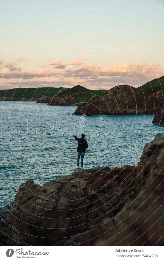 Anonymous traveler standing on rocky cliff near ocean anonymous sea tourist spectacular scenery nature breathtaking leisure wanderlust sunset admire cantabria