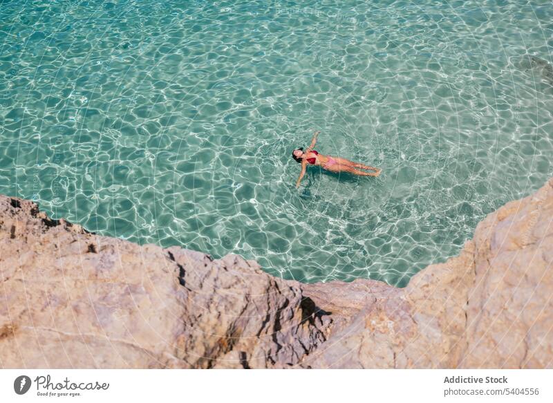 From above of young woman swimming in blue ocean tourist bikini float turquoise sea tropical resort female balearic islands swimwear swimsuit sunbath travel