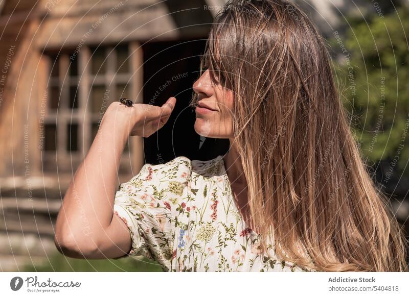 Charming woman with bug in summer countryside nature insect enjoy harmony catch hold carefree content meadow gentle freedom wild specie fauna creature wildlife