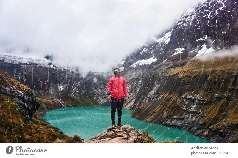 Man traveler standing on cliff by river mountain hill admire nature top volcano snow landscape valley picturesque adventure altar cloudy highland scenic winter