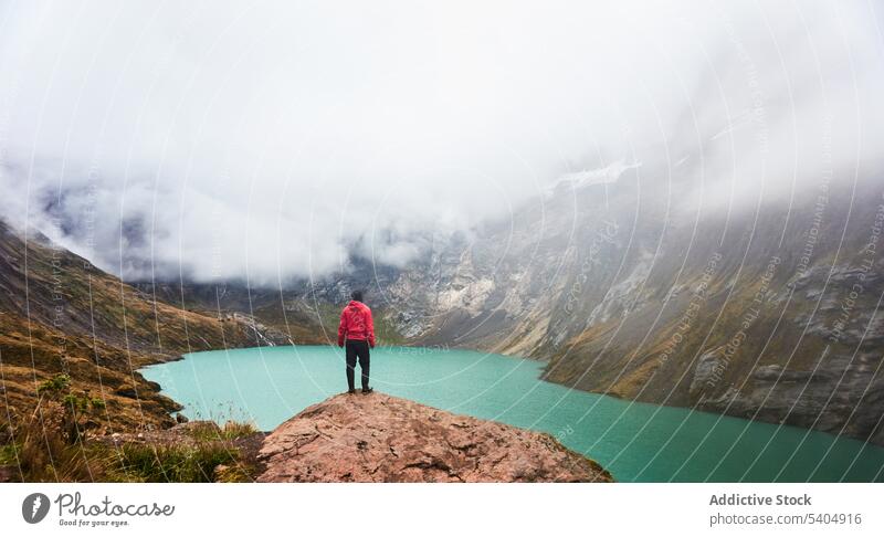 Unrecognizable man traveler standing on cliff by river mountain hill admire nature top volcano snow landscape valley picturesque adventure altar cloudy highland