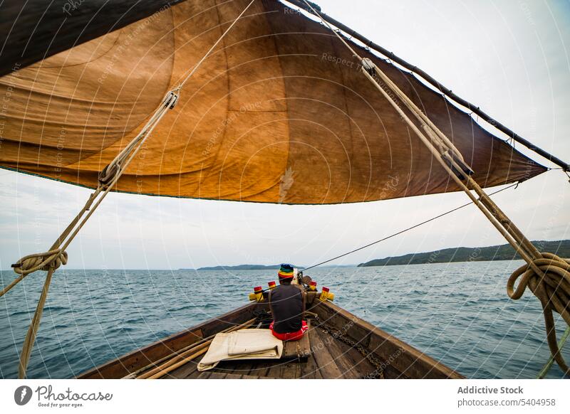 Anonymous man sitting on boat in rippling sea fisherman sailboat fishing float ripple wavy seawater calm endless transport ocean seascape deck voyage boatman