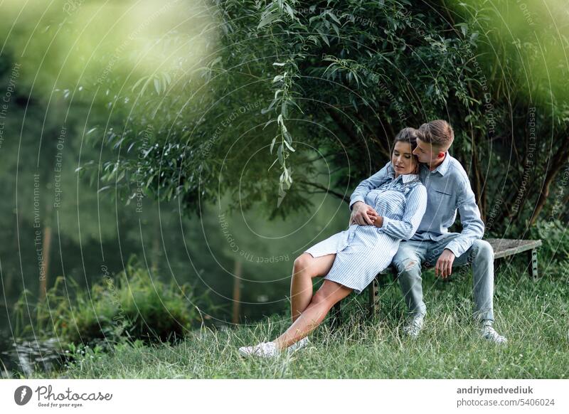 Young couple is hugging and sitting near the lake on sunny day. Man and woman on summer holiday. Concept of lovely family. selective focus young sunset walking