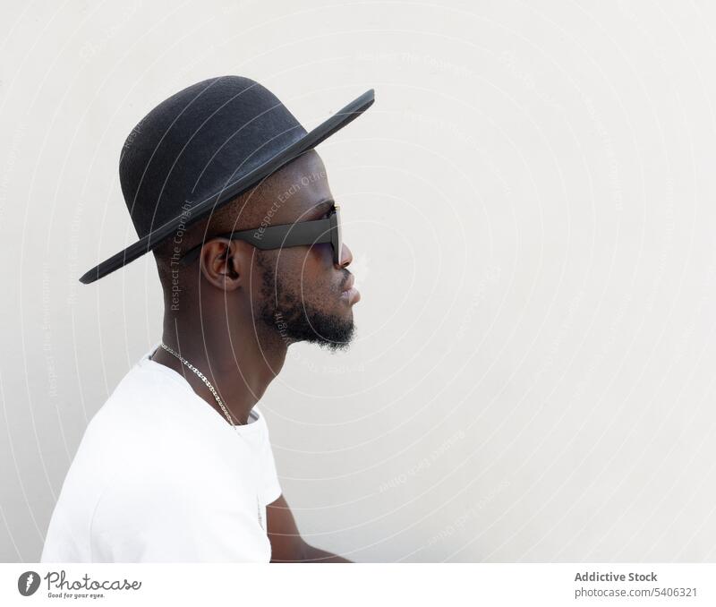 Cool young African American man sitting on stairs on street style self assured confident personality serious cool trendy sunglasses male african american black