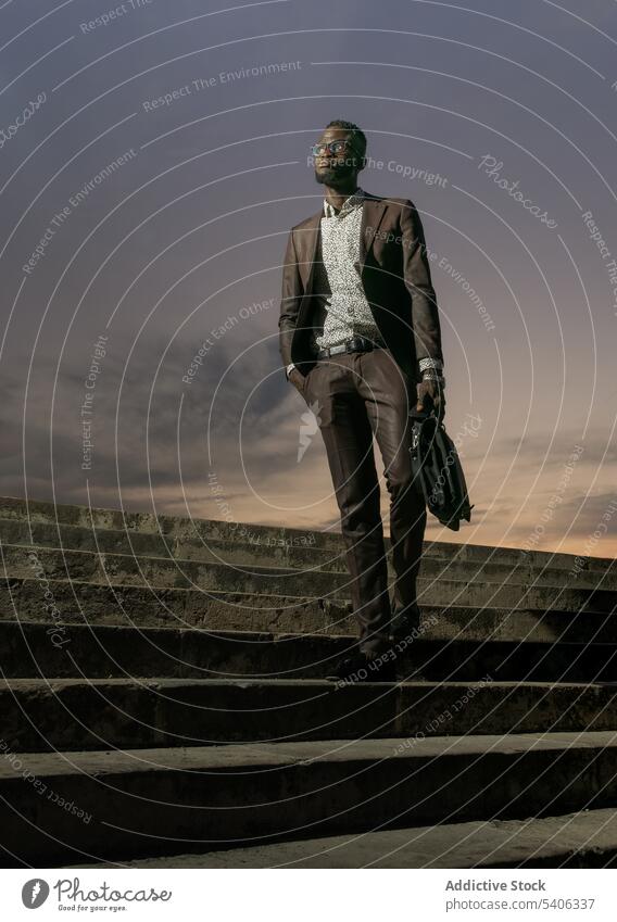 Young black businessman in suit standing on stairs elegant style briefcase urban confident staircase street entrepreneur well dressed determine serious