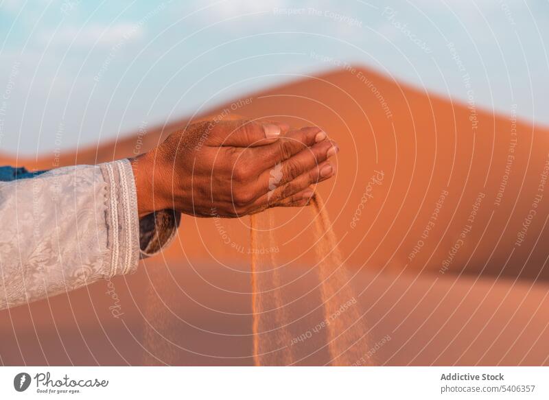 Sand falling from the hands of crop person in desert sand handful summer nature traveler tourism morocco merzouga daytime africa dry hot tranquil adventure trip