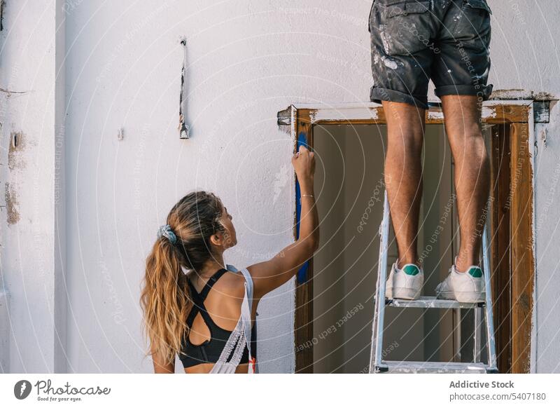 Couple painting wall at home during daytime couple dirty together renovate repair work improve apartment renewal relationship man woman room process creative