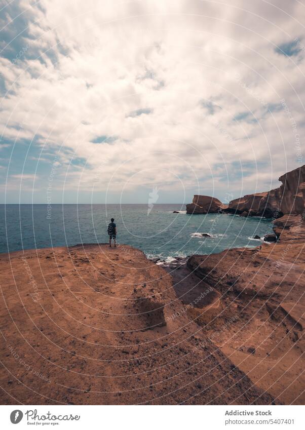 Unrecognizable male traveler standing on highland and admiring seascape person admire cliff rocky ocean wavy coast nature landscape tourist idyllic wave