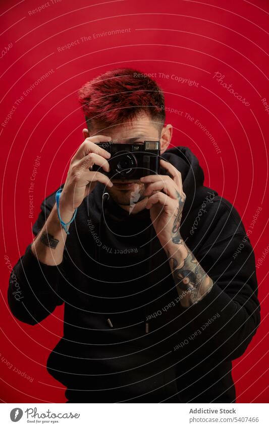 Young man taking photo on camera photo camera photographer portrait tattoo shoot dyed hair take photo studio lens style film creative retro trendy hairstyle