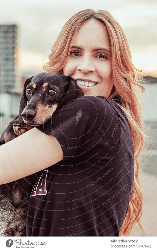 Happy female owner embracing dog on street woman hug care close dachshund love pet smile happy toothy smile young redhead casual long hair city canine loyal