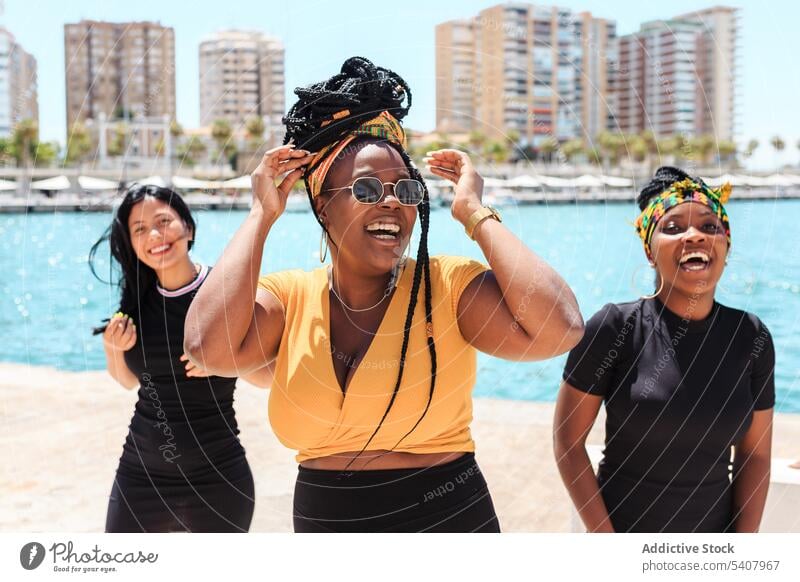 Group of cheerful multiethnic women in city friend stroll laugh together waterfront having fun summer group multiracial diverse black african american seafront