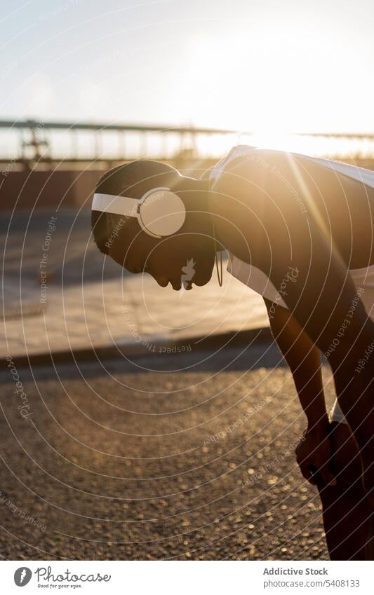 Exhausted black runner leaning on knee after running workout sportsman break training fitness rest fatigue exhausted athlete wellbeing strong jogger muscular