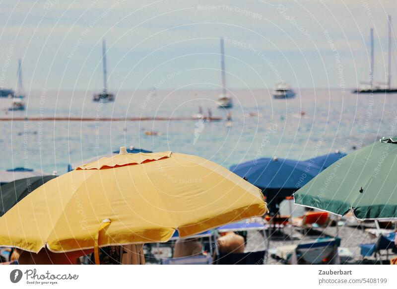 Parasols in yellow, blue and green, the sea behind, on the coast of the Italian Riviera Sunshade Yellow Blue Liguria Green stand Ocean Water boats bathe