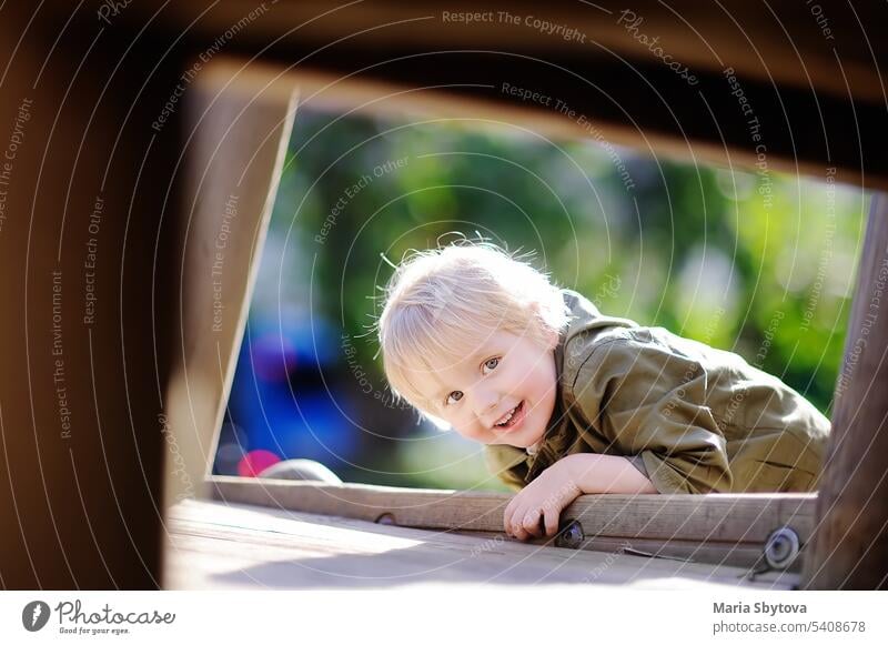 Happy little boy having fun on outdoor playground childhood happy kid kindergarten emotion leisure lifestyle equipment outside wooden autumn summer playful