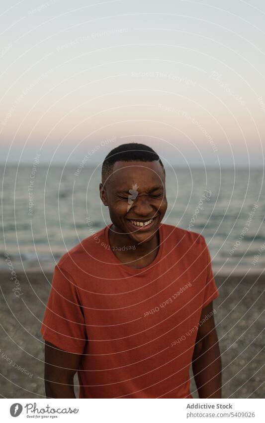 Cheerful black sportsman standing on beach african smiling closed eyes fit strong male sporty serious guy muscle shore confident torso african american seashore