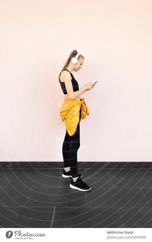 Young woman listening to music on the phone isolated on bright background young jogger headphones athlete runner running sport healthy fit fitness athletic