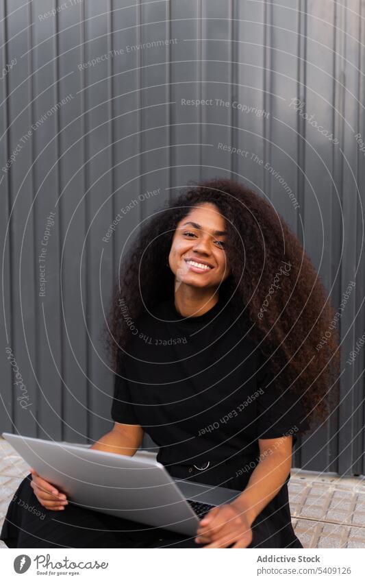 Cheerful African American self employed woman sitting on street with laptop freelance curly hair city entrepreneur ethnic black african american cheerful