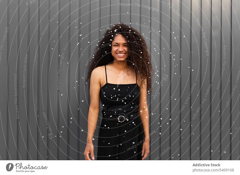 Black woman scattering confetti on street toss having fun cheerful delight festive celebrate event female ethnic black african american city happy joy smile