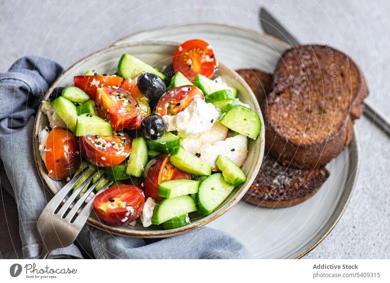 Delicious salad with vegetables and bread in plate bowl tomato cucumber slice onion healthy food portion fresh diet cutlery fork dish organic meal delicious