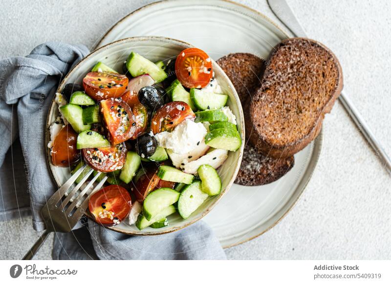 Delicious salad with vegetables and bread in plate bowl tomato cucumber slice onion healthy food portion fresh diet cutlery fork dish organic meal delicious