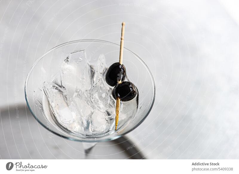 Martini cocktail with black olives on table martini alcohol beverage drink aperitif glass flavor booze taste delectable refreshment edge tasty serve studio