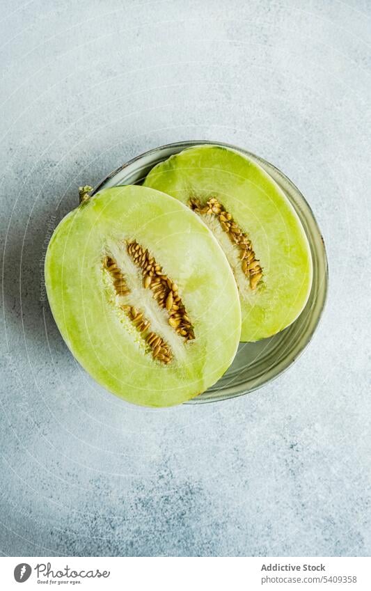 Honeydew green variety of melon fruit for dessert still life background pieces big white ceramic plate light colored glass table dish fresh healthy food