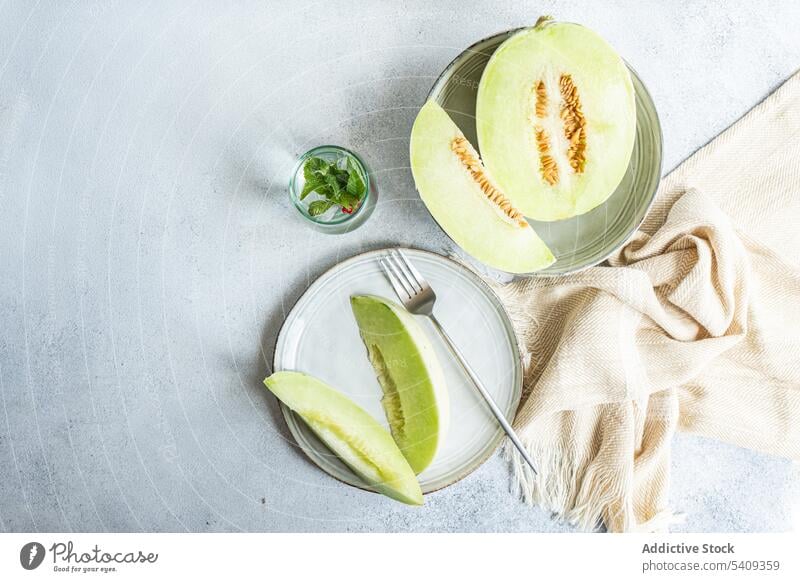 Honeydew green variety of melon fruit for dessert still life background pieces immature big drink white ceramic plate light colored glass table dish fresh