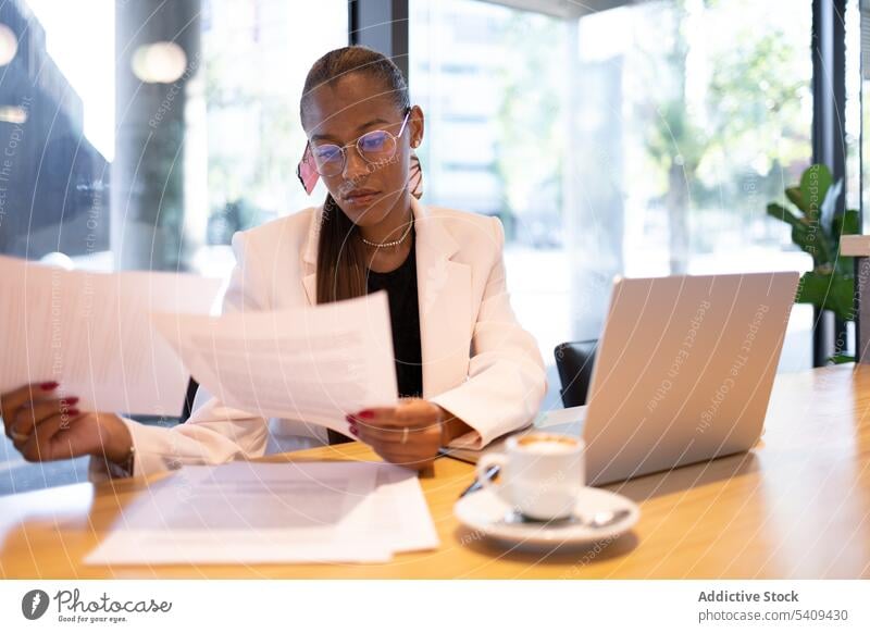 Focused woman doing paperwork in office businesswoman concentrate focus document read laptop coffee busy entrepreneur table workplace cup professional formal