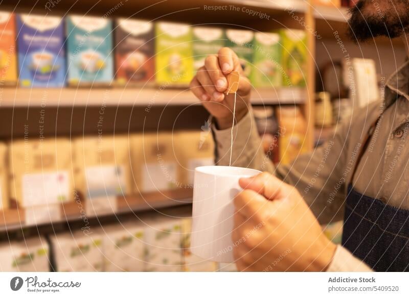 Anonymous man drinking hot tea in mug cup coffee store worker hot drink shop male choice employee modern purchase beverage shelf trade goods job occupation