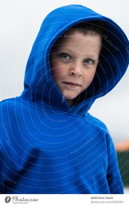 Calm adorable kid in blue hoodie standing in daylight child portrait confident cloudless sky calm innocent gaze summer boy preteen nature countryside childhood