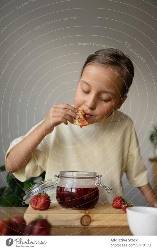 Cute girl eating pancake with fresh strawberry jam breakfast food fruit sweet tasty meal homemade yummy kid table natural preteen closed eyes delicious slice