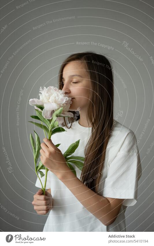 Calm preteen girl child standing with eyes closed with blooming peony flower with stem dreamy gentle blossom portrait delicate kid tender childhood floral