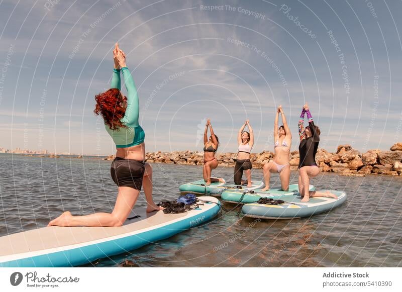 Group of women doing yoga in warrior 1 pose beach stretch practice balance warrior pose exercise activity coast kneel position wellbeing female ocean wellness