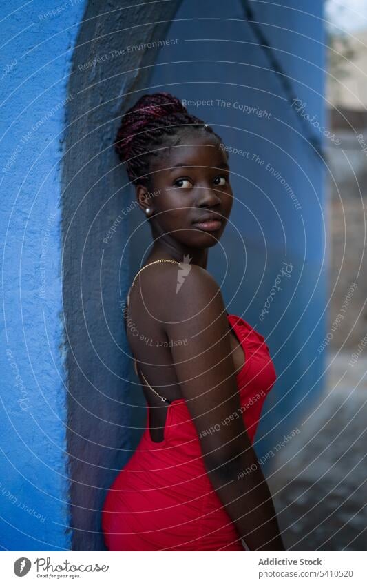 African American woman in red dress thoughtful pensive wall style trendy fashion outfit think lean calm dreamy stand personality braids lean on model modern